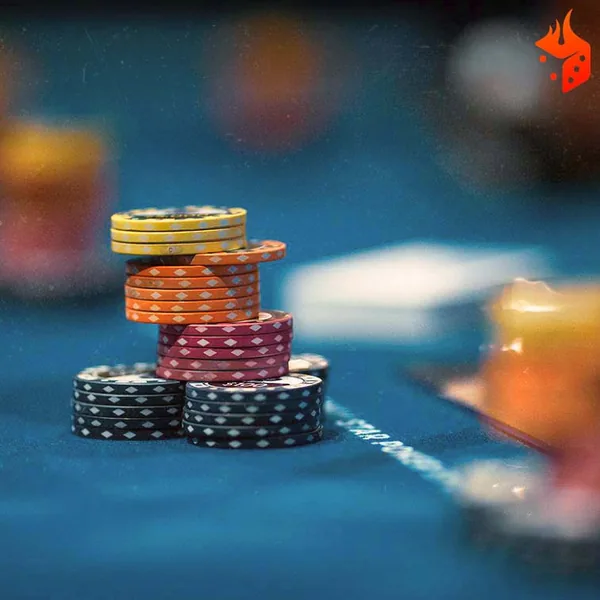 Pilha de fichas de poker coloridas sobre o feltro azul da mesa, com o símbolo da Ignition no canto